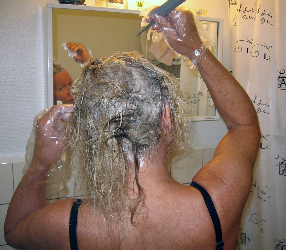 woman dyeing hair in front of the mirror